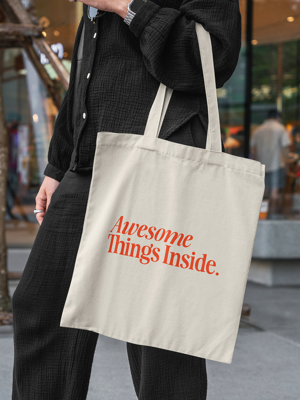 Frau trägt eine beigefarbene Stofftasche mit dem roten Statement-Print „Awesome Things Inside“ - ALMOST A BRAND