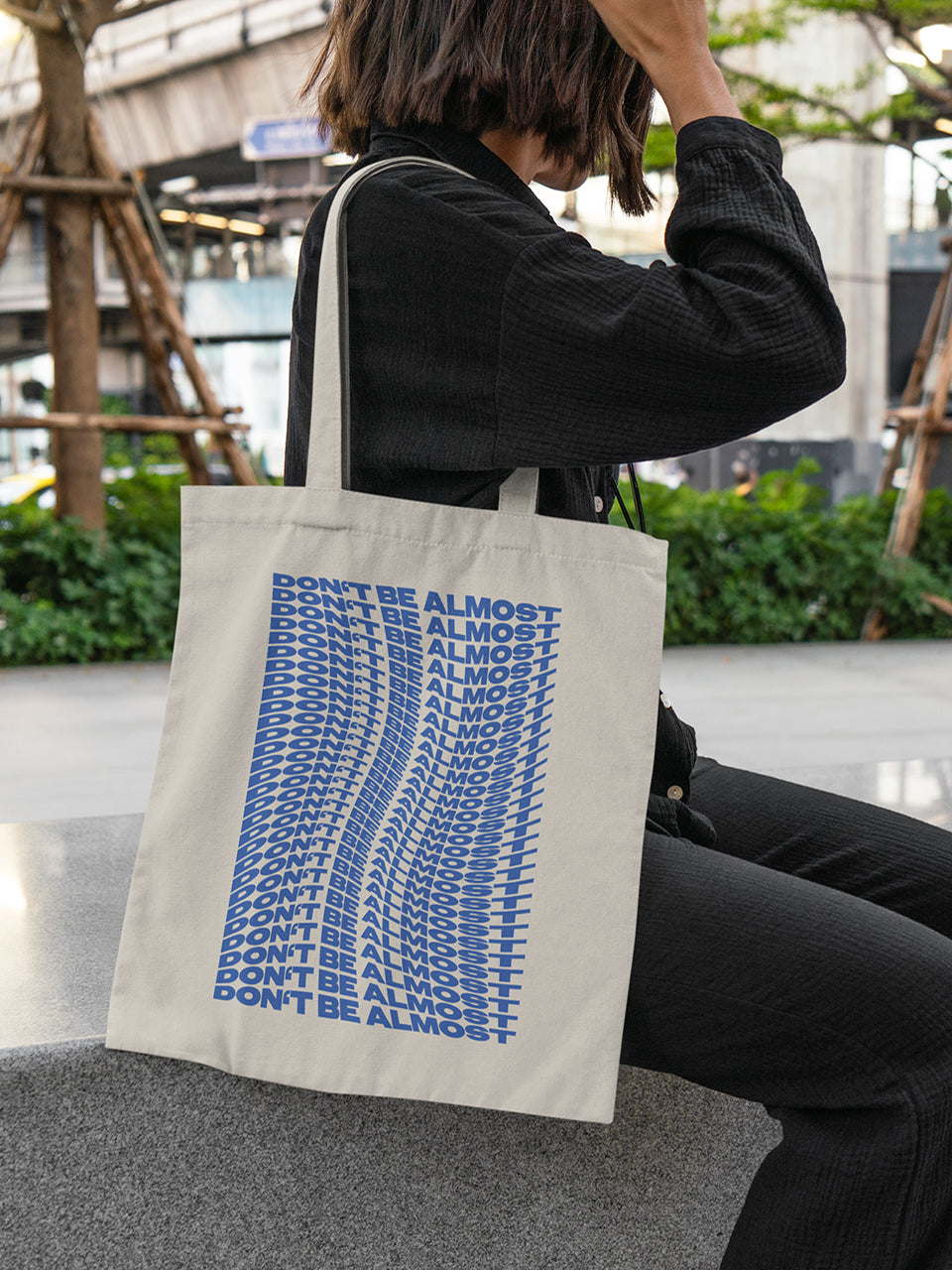 Beigefarbene Stofftasche mit wellenförmigem blauen Print „DON’T BE ALMOST“ – ideal für Alltag, Uni oder Shopping.