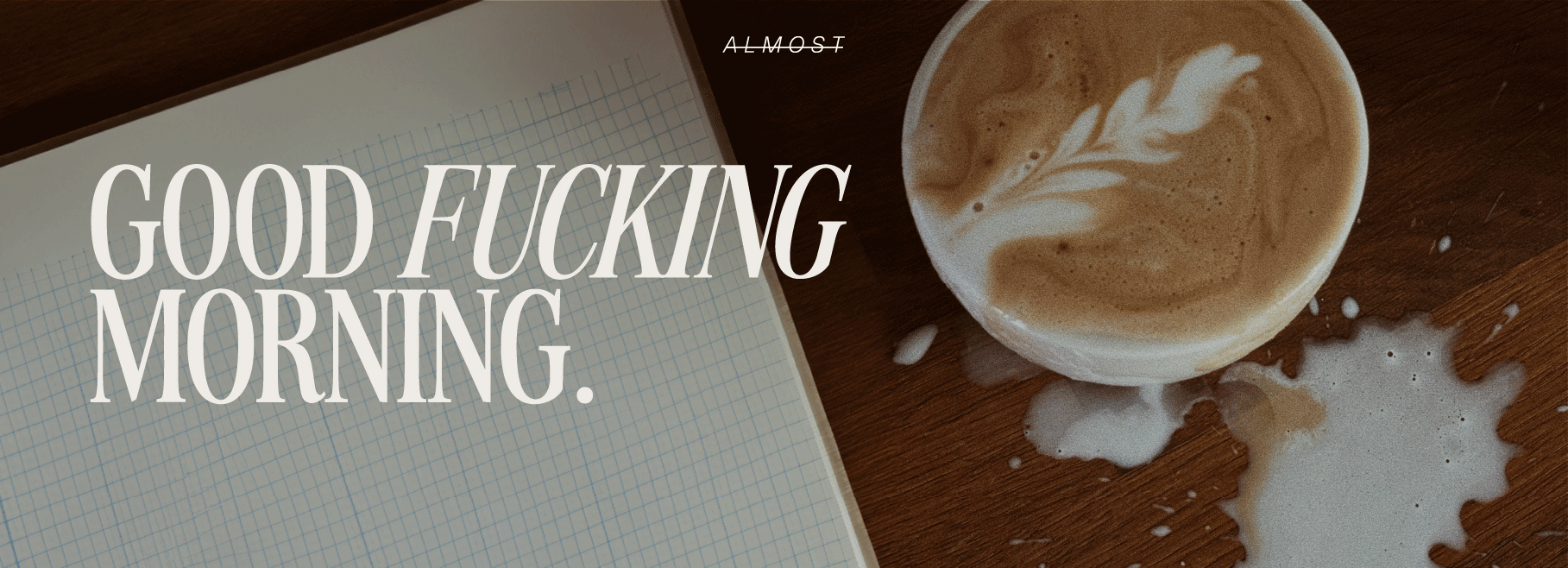 Latte-Art-Kaffee mit verschütteter Milch neben kariertem Notizbuch, darüber der Slogan „GOOD FUCKING MORNING.“