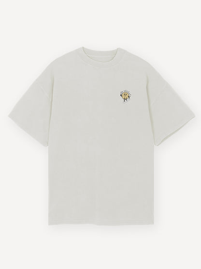 Vorderansicht eines weißen T-Shirts mit kleinem Print auf der linken Brustseite. Zu sehen ist eine freundliche, gezeichnete Sonne mit Gesicht und erhobener Hand in Comic-Stil.