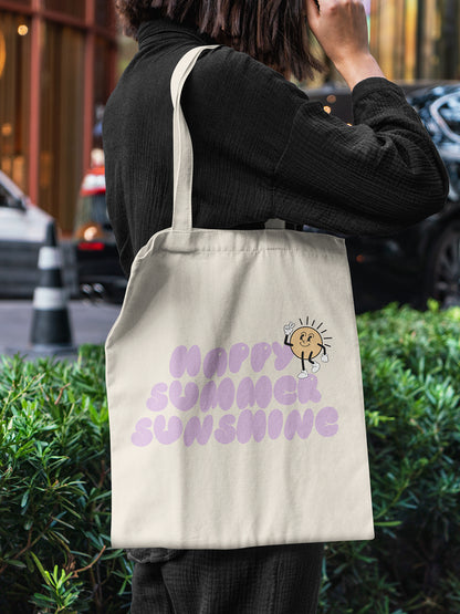 Frau mit beigefarbener Stofftasche, bedruckt mit lilafarbenem „Happy Summer Sunshine“-Schriftzug und lachender Cartoon-Sonne – ALMOST A BRAND